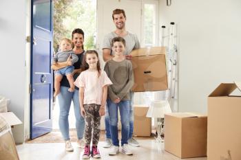 Portrait Of Family Carrying Boxes Into New Home On Moving Day