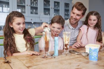 Father Making Ice Cream Sundaes With Children At Home