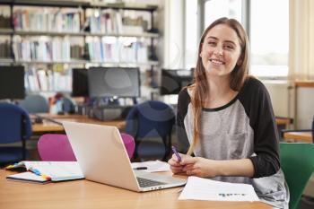 Portrait Of Female Student Working At Laptop In College Library