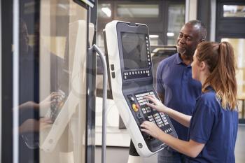 Engineer Showing Apprentice How To Use CNC Tool Making Machine