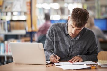 Mature Male Student Working On Laptop In College Library