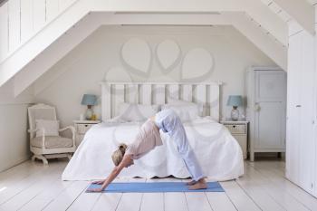 Woman At Home Starting Morning With Yoga Exercises In Bedroom