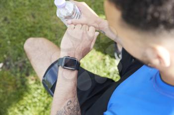 Young male athlete checking smartwatch, over shoulder view
