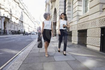 Two female colleagues walking in the street talking