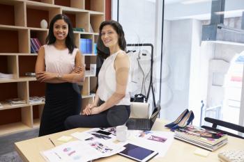 Two female creatives in an office smiling to camera