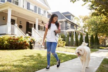 Girl Walking Dog Along Suburban Street