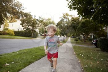 Toddler boy running in a quiet residential street