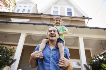 Father Giving Son Ride On Shoulders Outside House