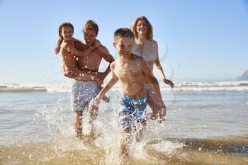 Family On Summer Beach Vacation Run Out Of Sea Towards Camera