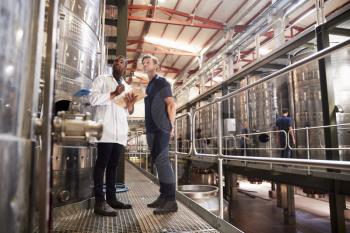 Two male technicians working at a wine factory, low angle