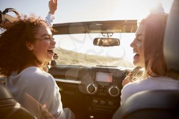 Young adult girlfriends having fun driving an open top car