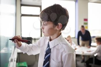 Male High School Student Wearing Uniform Using Interactive Whiteboard During Lesson