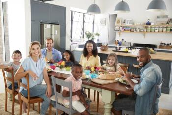 Two families having lunch together at home looking to camera