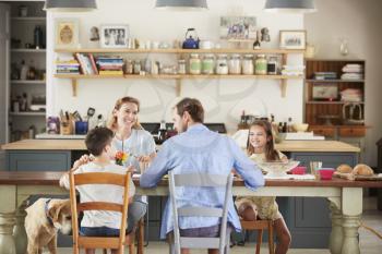 Family with dog eating together at the table in kitchen