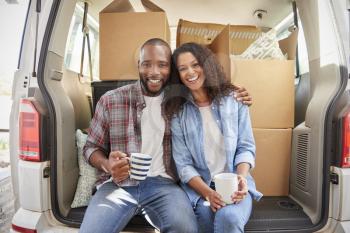 Couple Taking A Break In Back Of Removal Truck On Moving Day