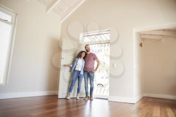 Couple Opening Door And Walking In Empty Lounge Of New Home