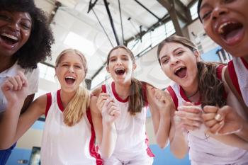 Portrait Of Female High School Basketball Team Celebrating With Coach