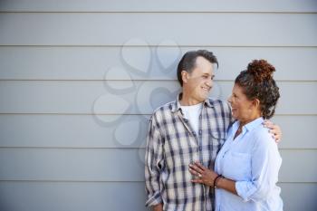 Senior Couple Standing Outside Grey Clapboard House