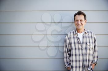Portrait Of Senior Man Standing Outside Grey Clapboard House
