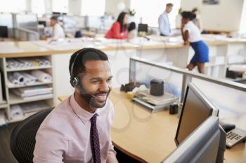 Smiling black male call centre worker looking at screen