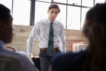 Young male manager listening to team at a meeting, close up