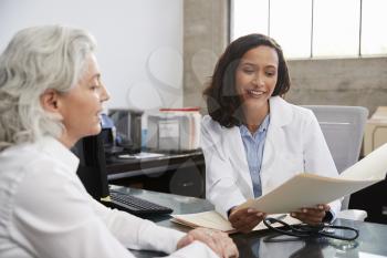Smiling female doctor in consultation with senior patient
