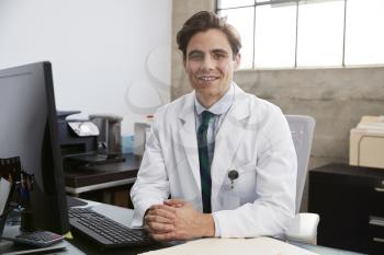 Young white male doctor at desk, portrait