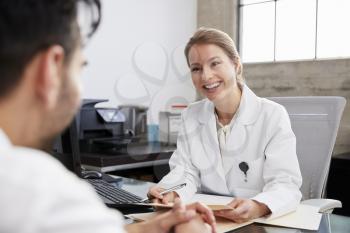 Smiling female doctor in consultation with male patient