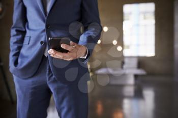 Mid section of man in blue suit using smartphone, close up