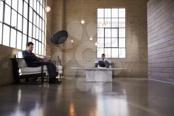 Two men sitting in the foyer of a business building