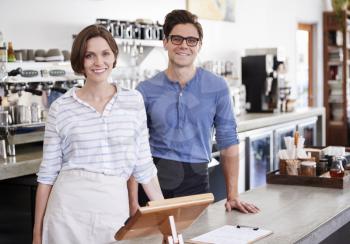 Happy young man and woman behind the counter at coffee shop