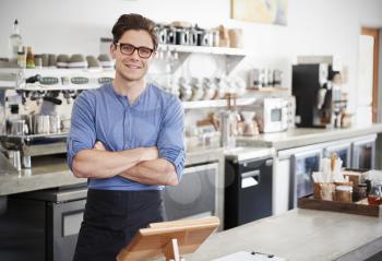 Male coffee shop owner behind the counter, arms crossed