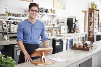 Male coffee shop owner behind the counter at his coffee shop