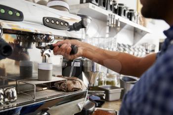 Young male barista preparing espresso at a cafe, close up