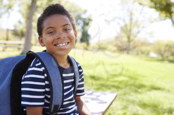 Young mixed race schoolboy with backpack smiles to camera