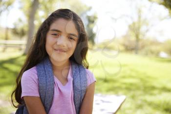 Young Hispanic schoolgirl looks to camera, smiling