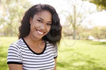 Outdoor Head And Shoulders Portrait Of Smiling Young Woman In Park
