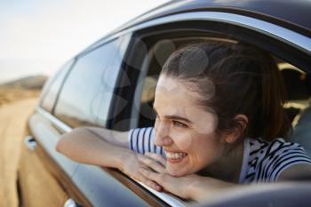 Smiling Woman Looking Out Of Car Window Enjoying Road Trip