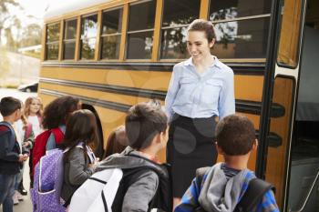 School teacher preparing kids to get on the school bus
