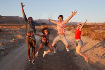 Young adult friends having fun jumping in the desert