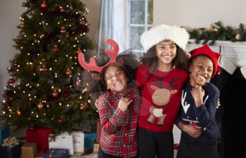 Portrait Of Children Wearing Festive Jumpers And Hats Celebrating Christmas At Home Together