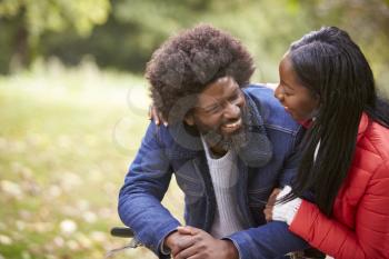 Black couple embracing and looking at each other smiling in a park, close up