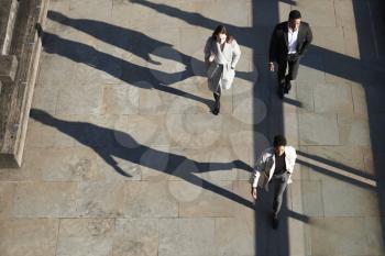 Aerial view of three city workers walking on a sunny urban street, horizontal