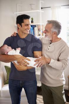 Proud senior Hispanic man standing with his adult son holding his four month old boy, vertical