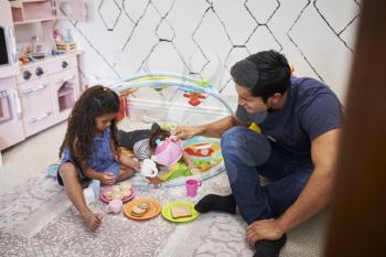 Young girl playing tea party with dad, sitting on the floor, baby brother beside them, elevated view