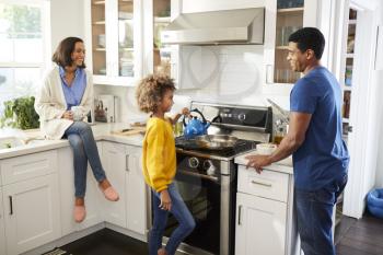 Mixed race parents and their daughter spending time together preparing food in the kitchen
