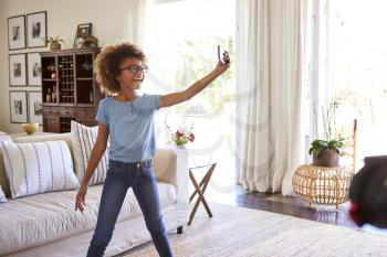 Pre-teen girl filming herself singing using a social media app on her smartphone