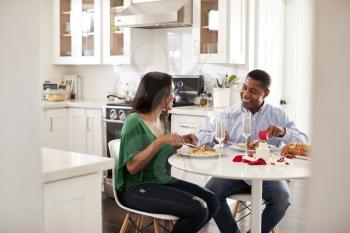 Middle aged mixed race couple eating a romantic meal together in their kitchen, close up