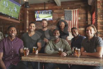 Group Of Friends Meeting And Drinking Beer In Sports Bar Together At Camera