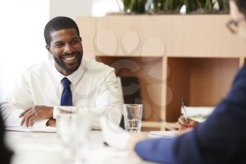 Two Businessmen Sitting Around Table Meeting In Modern Open Plan Office